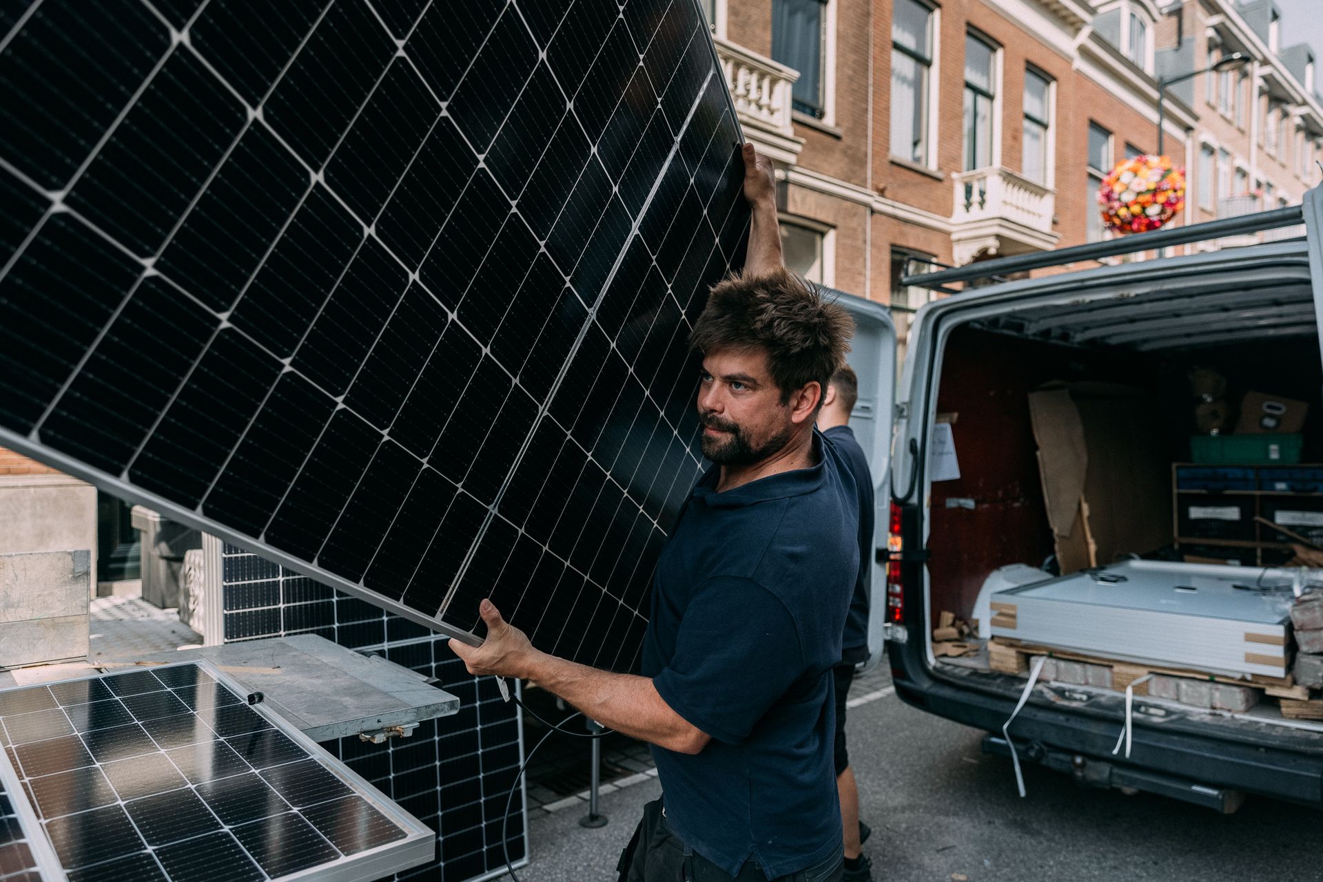 Monteur van VolopZon met een zonnepaneel bij de bedrijfsbus